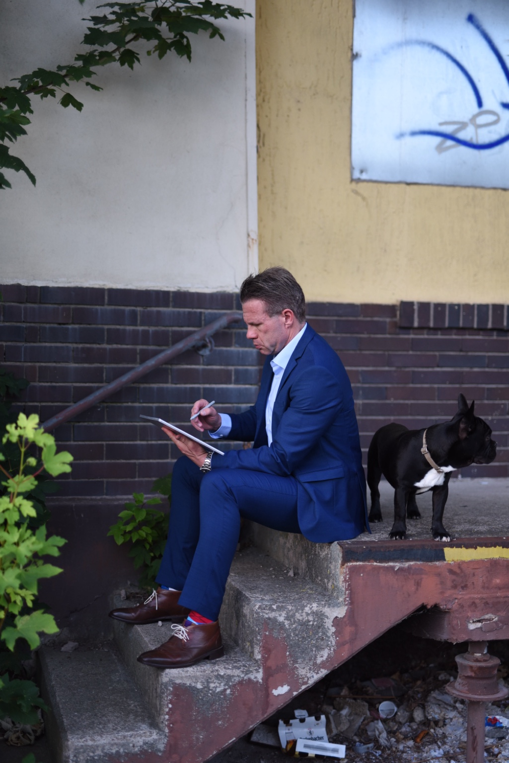 Raphael Slowik arbeitet auf einer Berliner Hinterhoftreppe, neben ihm sein Hund Hugo